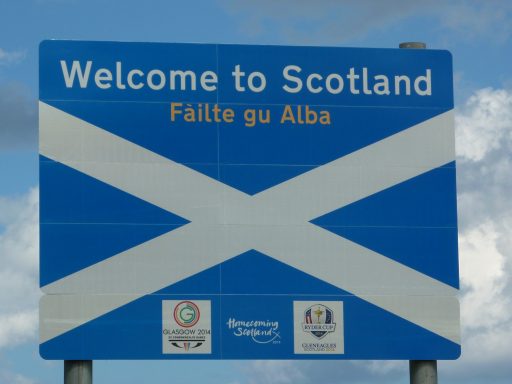 Willkommensschild für Schottland mit dem schottischen Kreuz und mehrsprachigem Text.