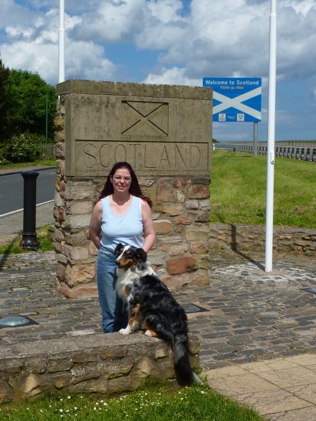 Elke mit Hund vor dem Stein und Schild an der Grenze zu Schottland